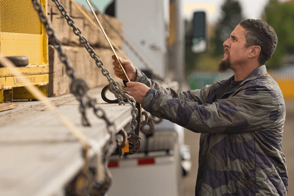 A Truckstop.com user checking straps on a flatbed trailer.