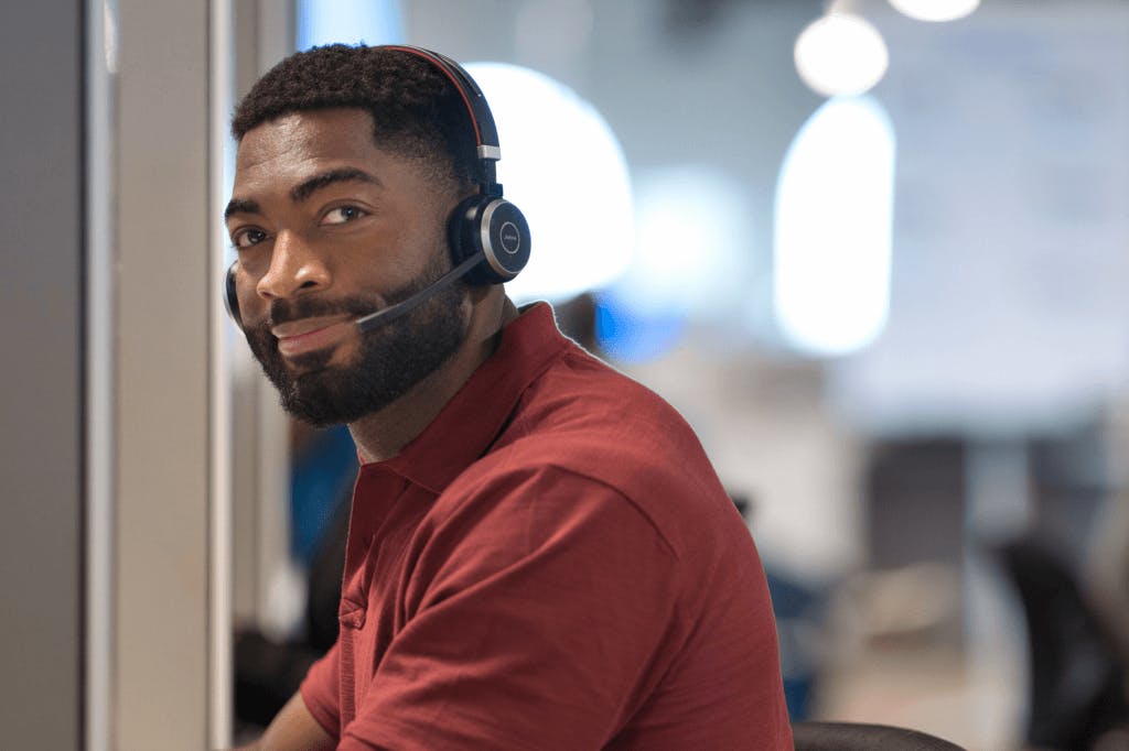 Seated bearded man wearing headset and slightly smiling