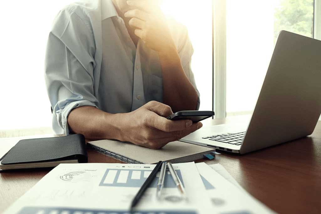 person sitting at desk holding mobile phone