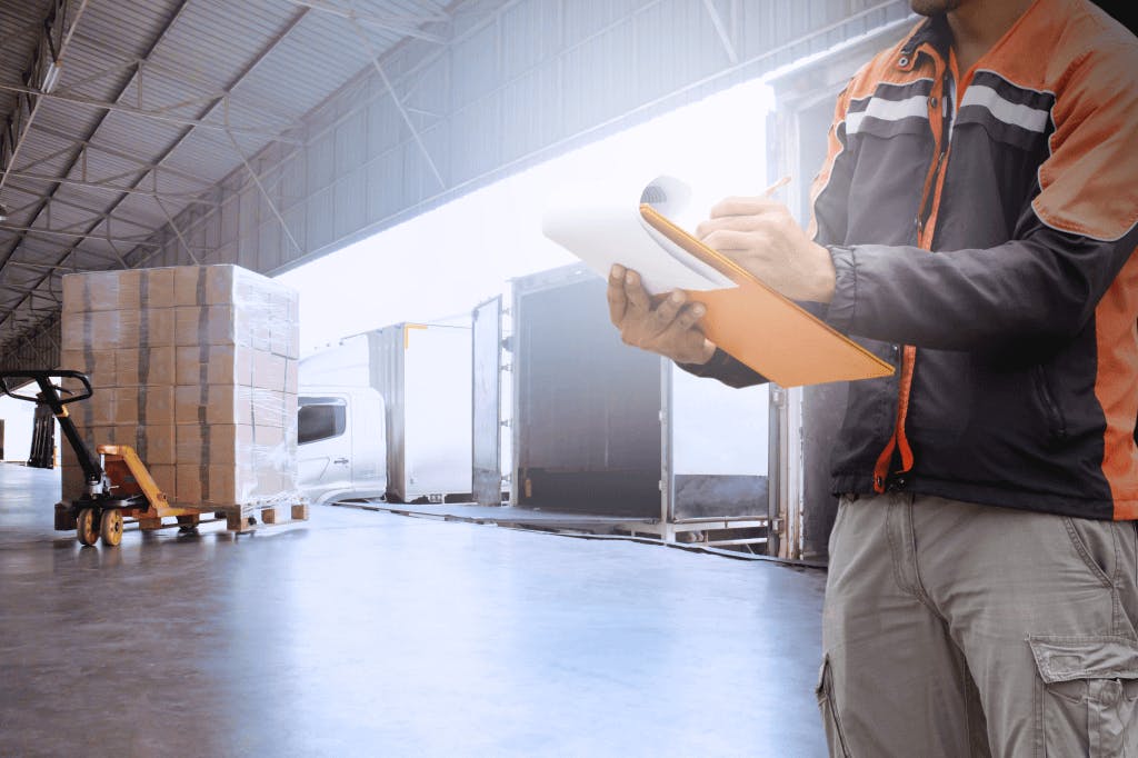 Consolidated freight quality control professional with clipboard unloading trailer