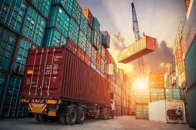 Crane moving shipping container in busy shipyard during drayage shortage