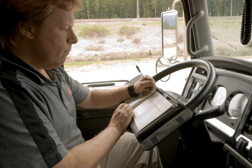 Truck driver updating IFTA mileage logbook for fuel tax reporting