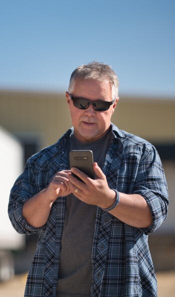 A truck driver uses his phone to find expedited loads on Truckstop.