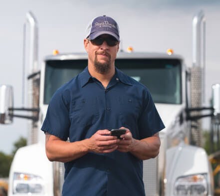 Carrier standing in front of his truck using the Truckstop mobile app.