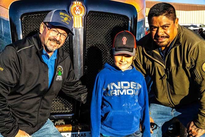 Jesus Davila and Tim Dean standing with child in front of truck