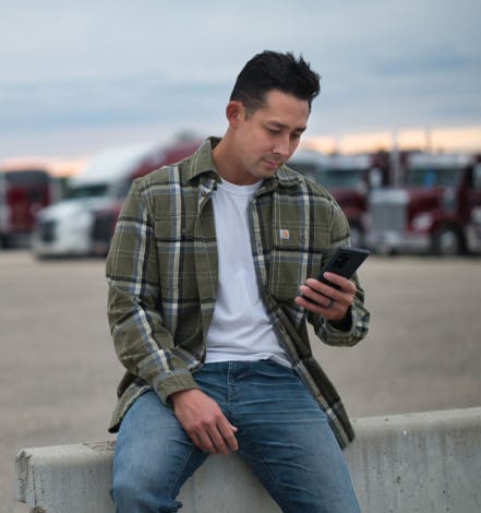 A trucker driver checks his Truckstop app while at the truck stop.
