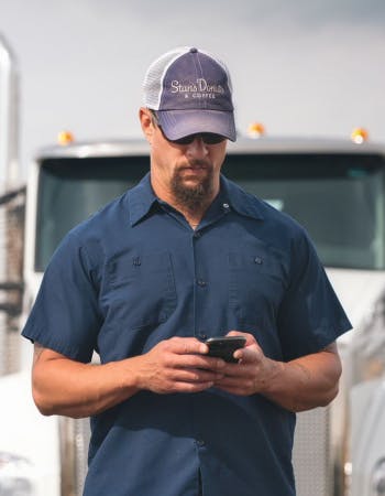 A truck driver uses his phone to find expedited loads on Truckstop.