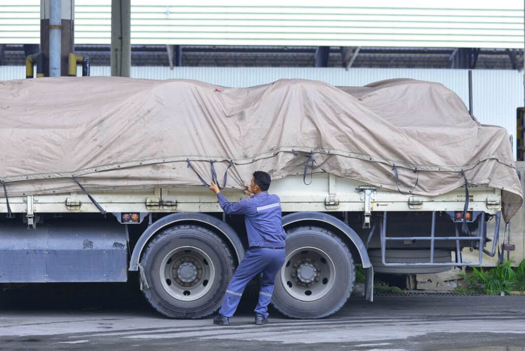 A truckstop.com user covering a flatbed load with a tarp.