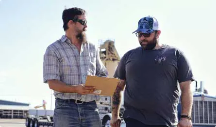 Two carriers reviewing paperwork at a truck yard